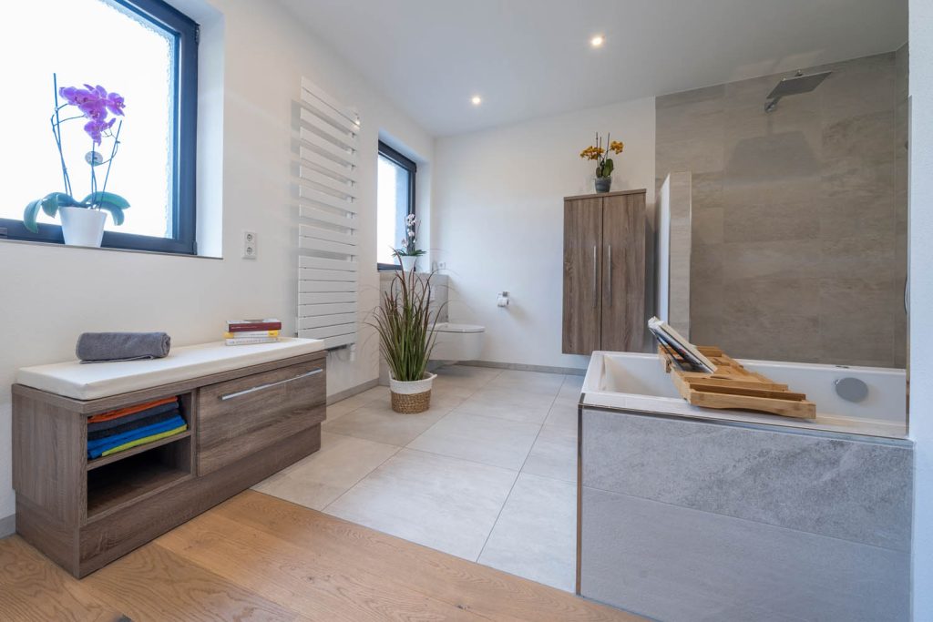 Sitzbank mit Stauraum unter dem Fenster, rechts Badewanne mit Holzablage