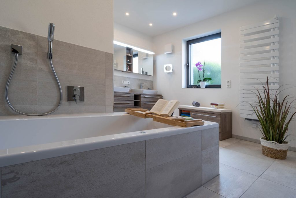Badewanne im Vordergrund, dahinter Waschtisch, Fenster und Heizkörper