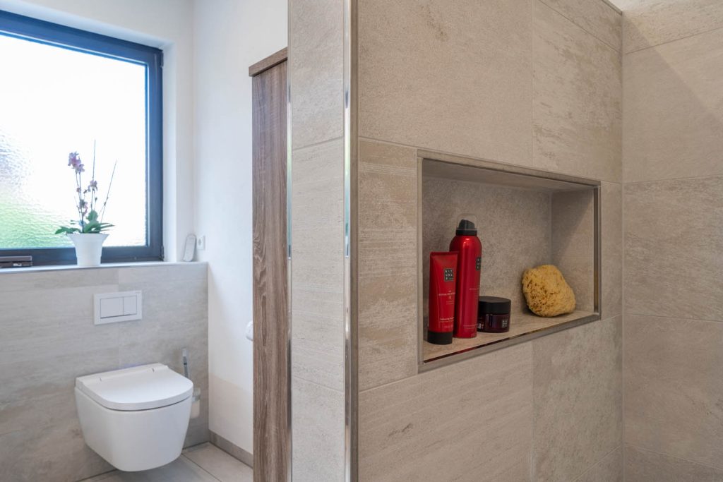 Wandnische mit Pflegeprodukten in der Trennwand neben dem WC