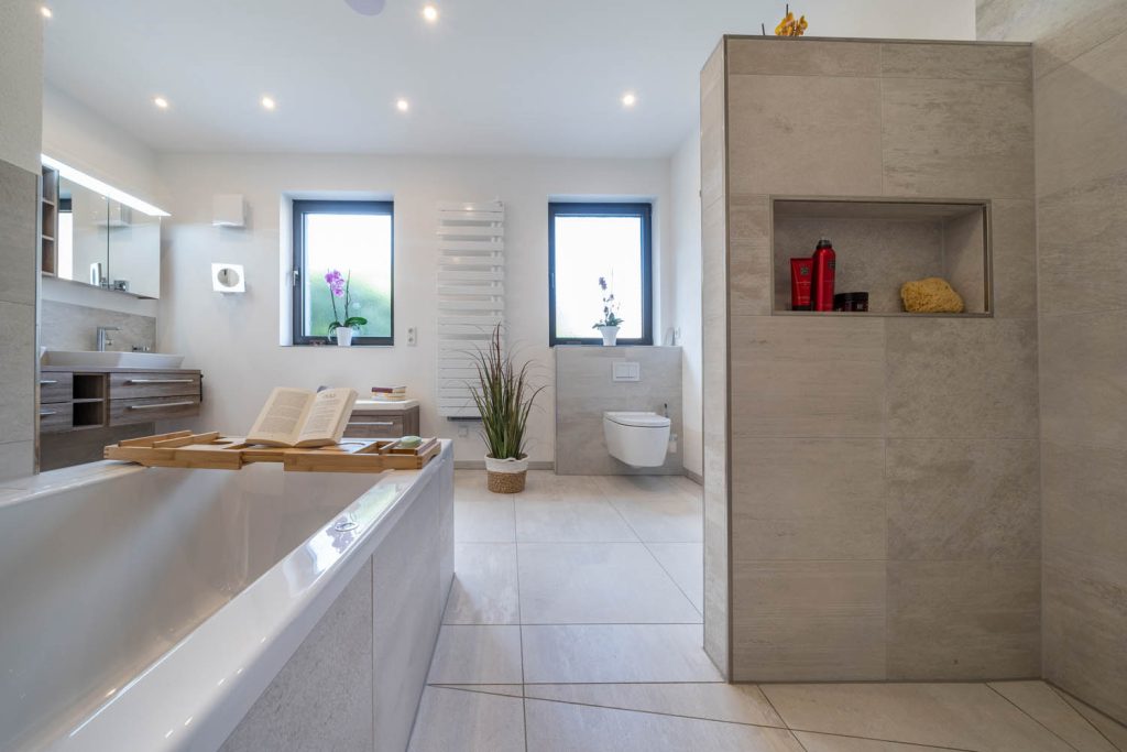 Badewanne und Trennwand mit Nische, im Hintergrund zwei Fenster