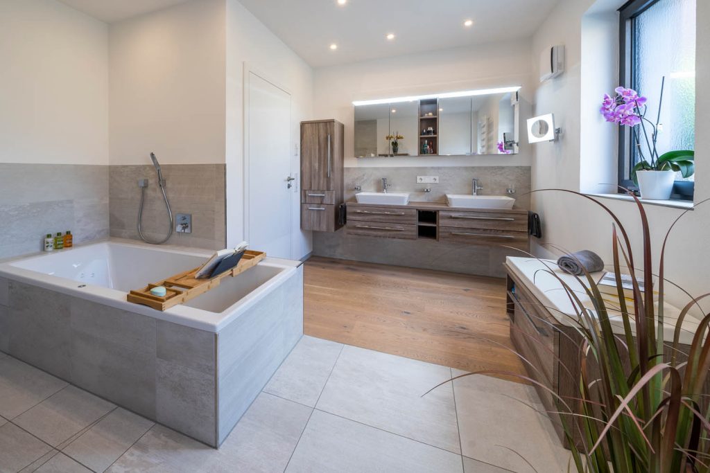 Badewanne im Vordergrund, dahinter Waschtisch mit Spiegelschrank