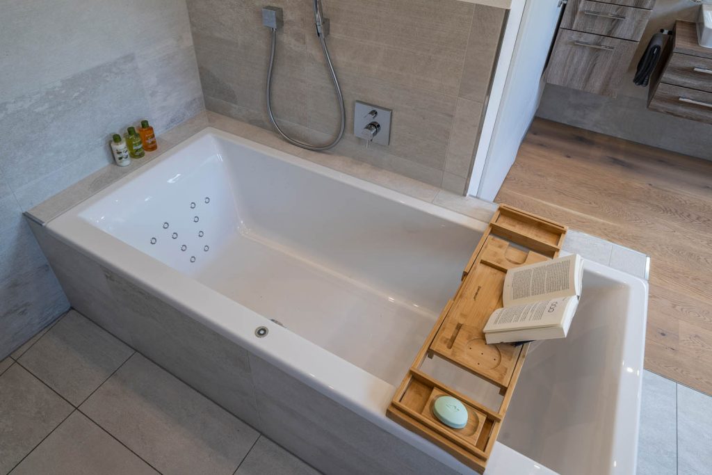 Badewanne mit Massagedüsen und Wannenablage aus Holz