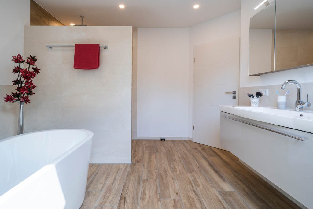 Freistehende Wanne neben einer gefliesten Trennwand mit Handtuchstange