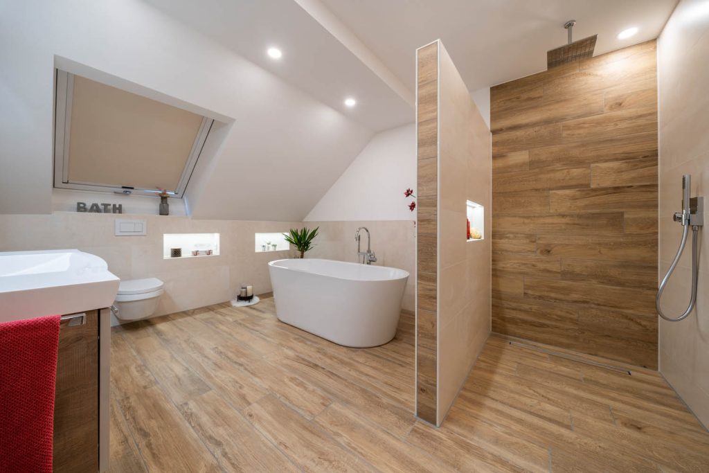 Blick zur Dusche mit Rückwand in Holzoptik, links Wanne unter dem Dachfenster