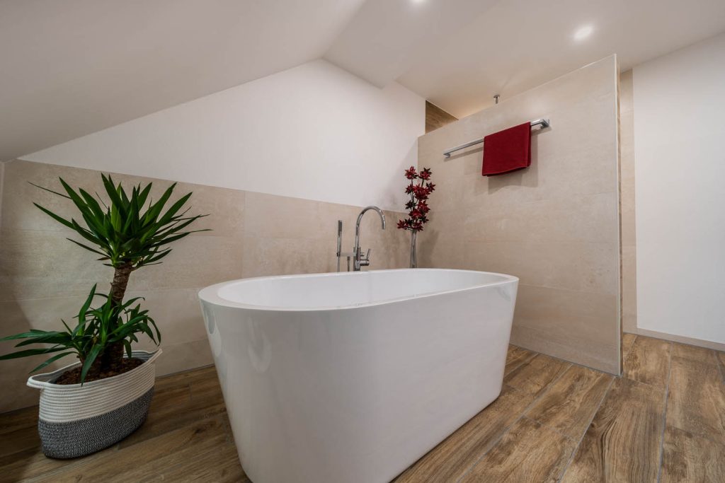 Ovale Badewanne mit Standarmatur und Pflanze im Korb