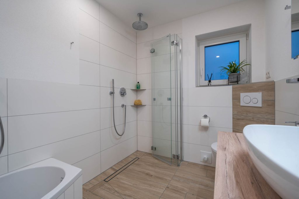 Bodengleiche Dusche mit Glas-Falttür und Duschrinne unter dem Fenster