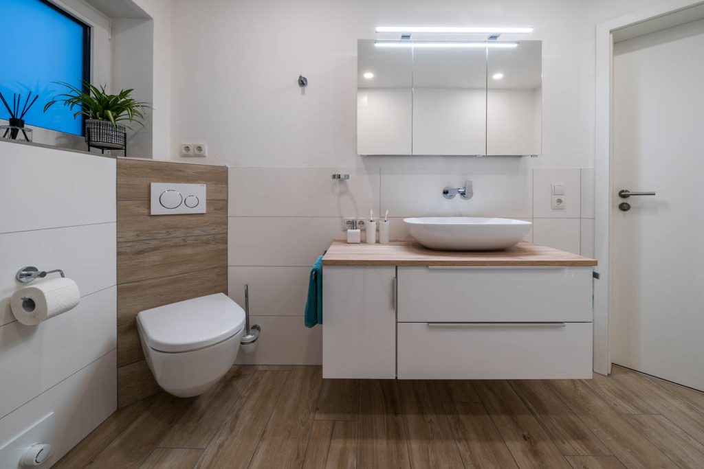 Waschtisch mit Holzplatte und Spiegelschrank, links Wand-WC