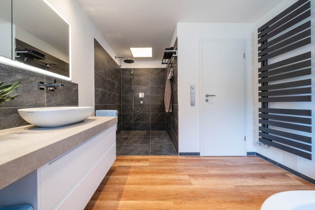 Blick in die begehbare Dusche in Anthrazit, rechts schwarzer Handtuchheizkörper