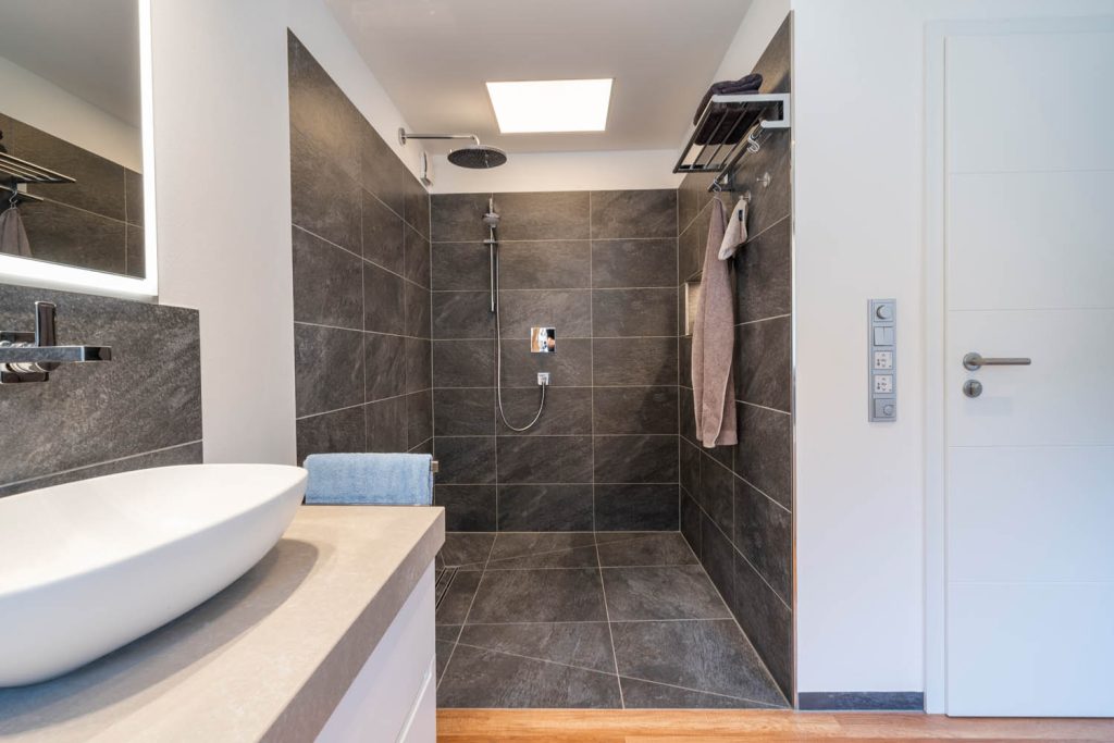 Walk-in-Dusche mit dunklen Fliesen, Regenbrause und Oberlicht