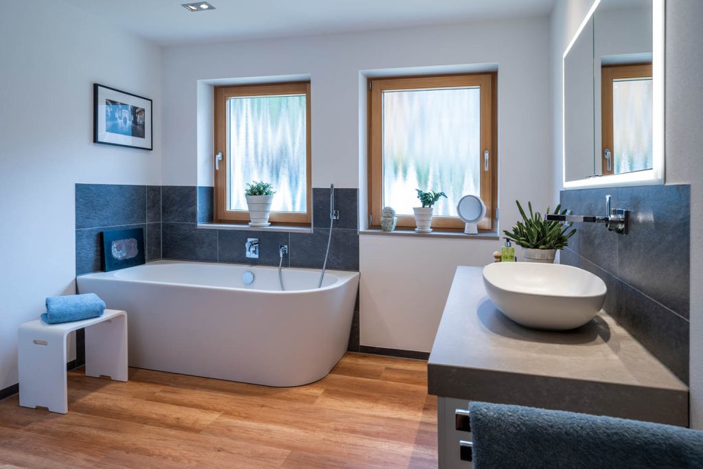 Raumansicht mit Wanne, Fenstern und Waschtisch mit Aufsatzbecken