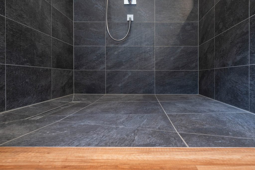 Ebener Duschboden in Anthrazit mit Handbrause an der Wand