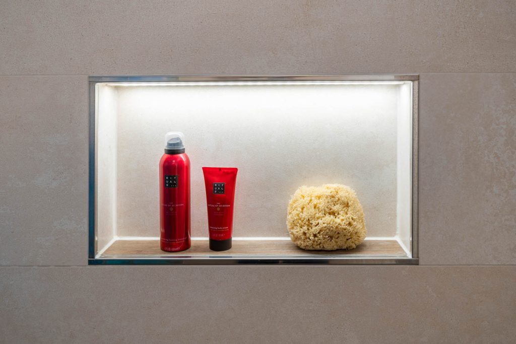 Beleuchtete Nische mit Pflegeprodukten in der Dusche