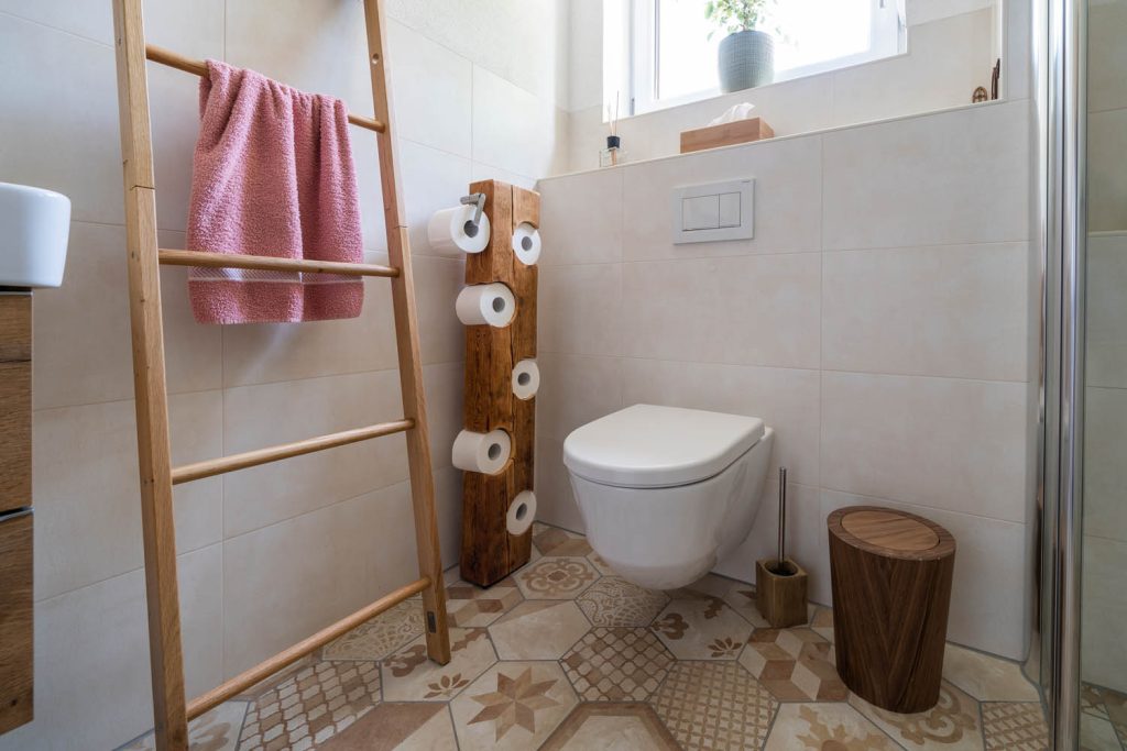 Wand-WC vor gefliester Vorwand, daneben Holzleiter und Papierständer