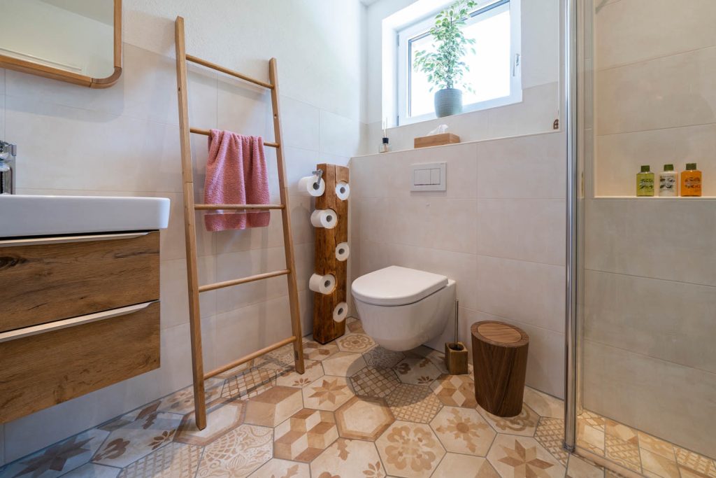 Wand-WC unter dem Fenster, links Holzleiter mit rosa Handtuch