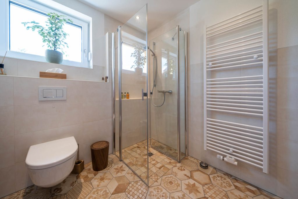 Bodengleiche Glasdusche zwischen WC und weißem Heizkörper