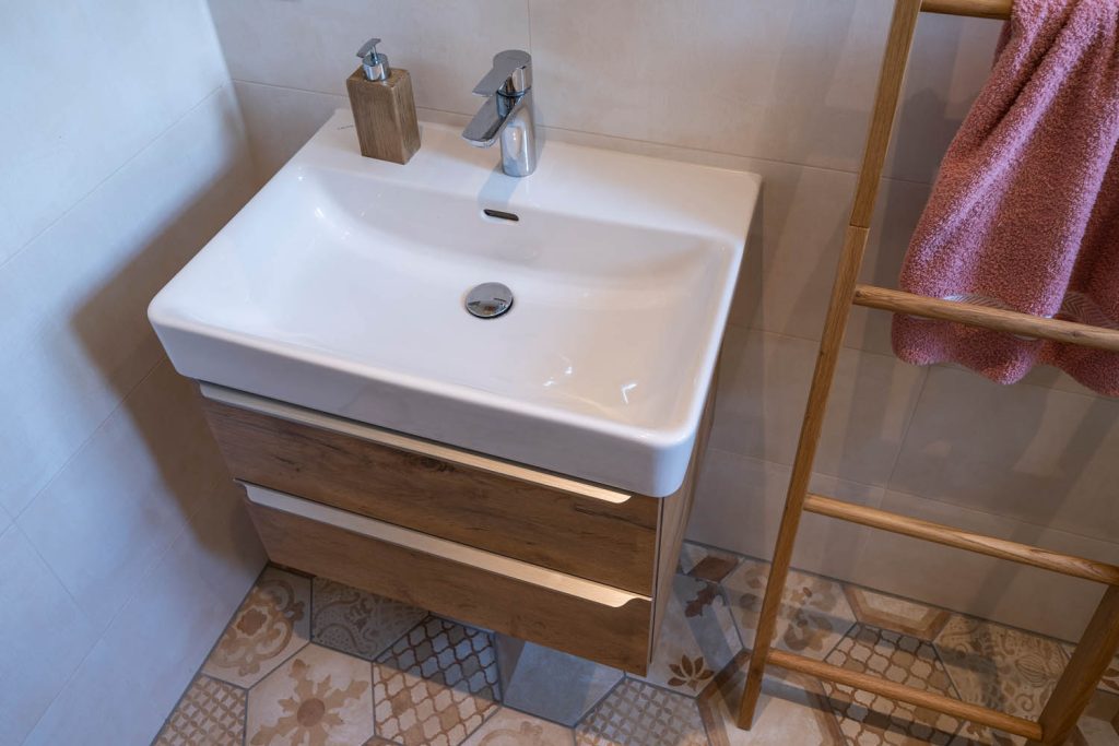 Waschbecken auf Holzunterschrank mit Armatur und Seifenspender