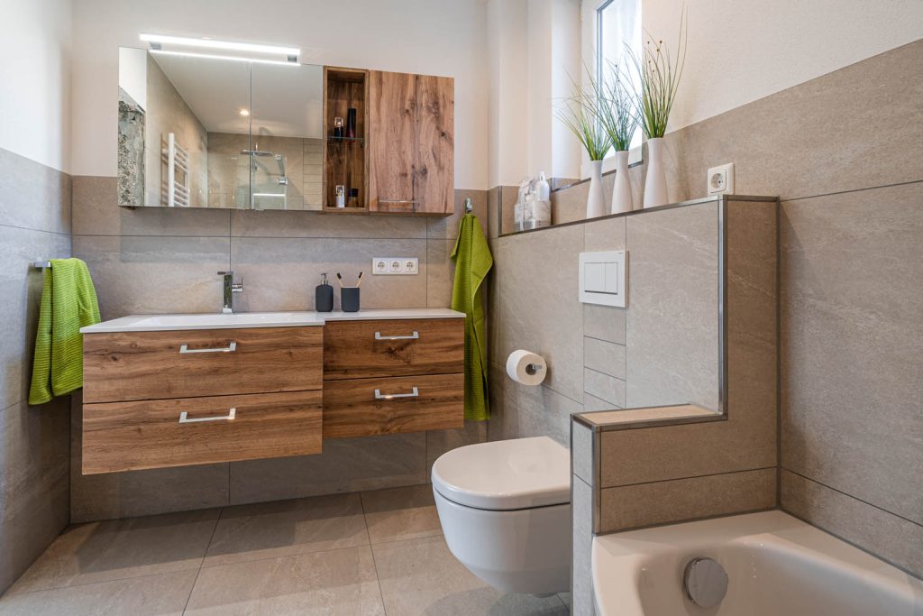 Waschtisch und Wand-WC, im Vordergrund der Rand der Badewanne