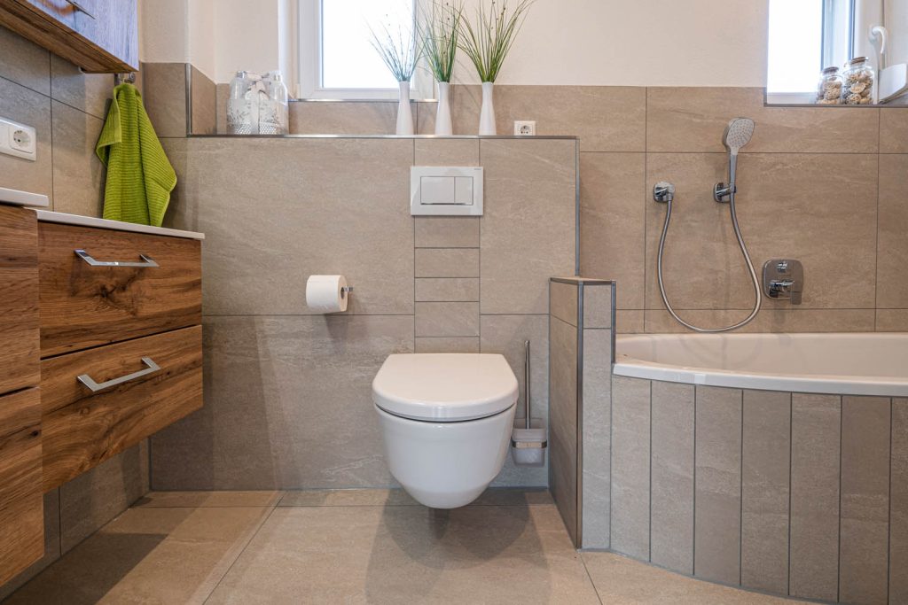 Wand-WC vor Vorwand, rechts Eckwanne mit Handbrause