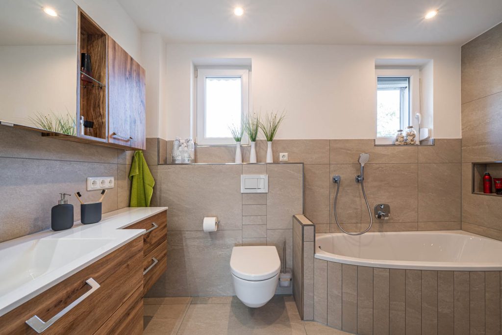 Waschtisch, Wand-WC und Badewanne unter zwei Fenstern