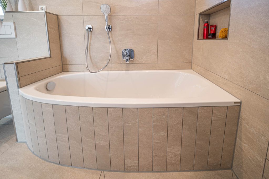 Eckbadewanne mit gefliester Schürze und Nische
