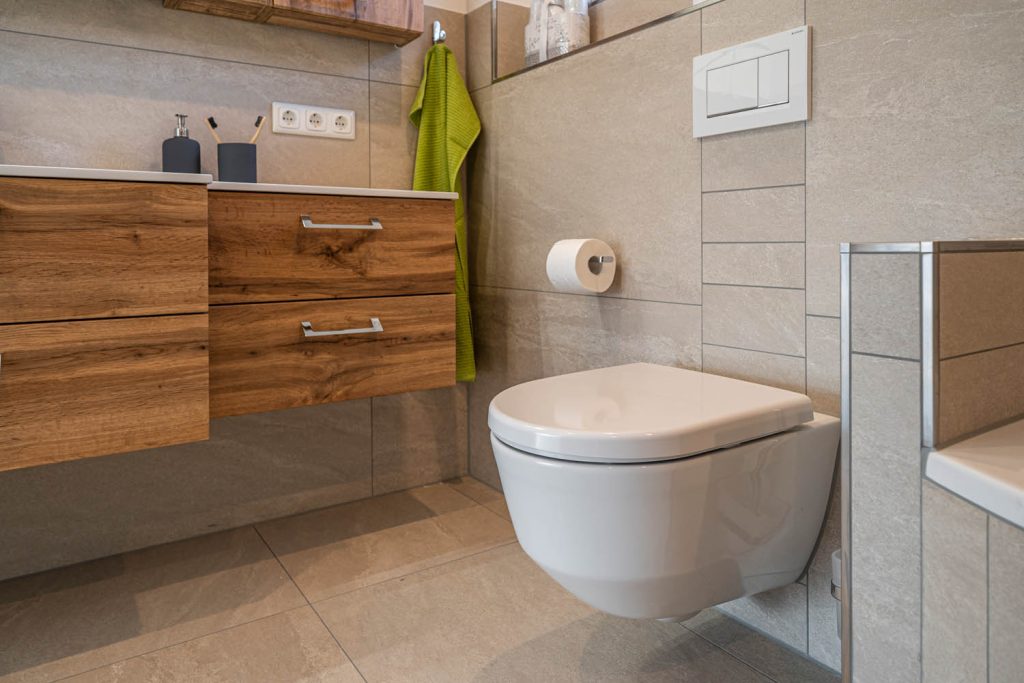 Wand-WC neben dem Unterschrank in Holzoptik