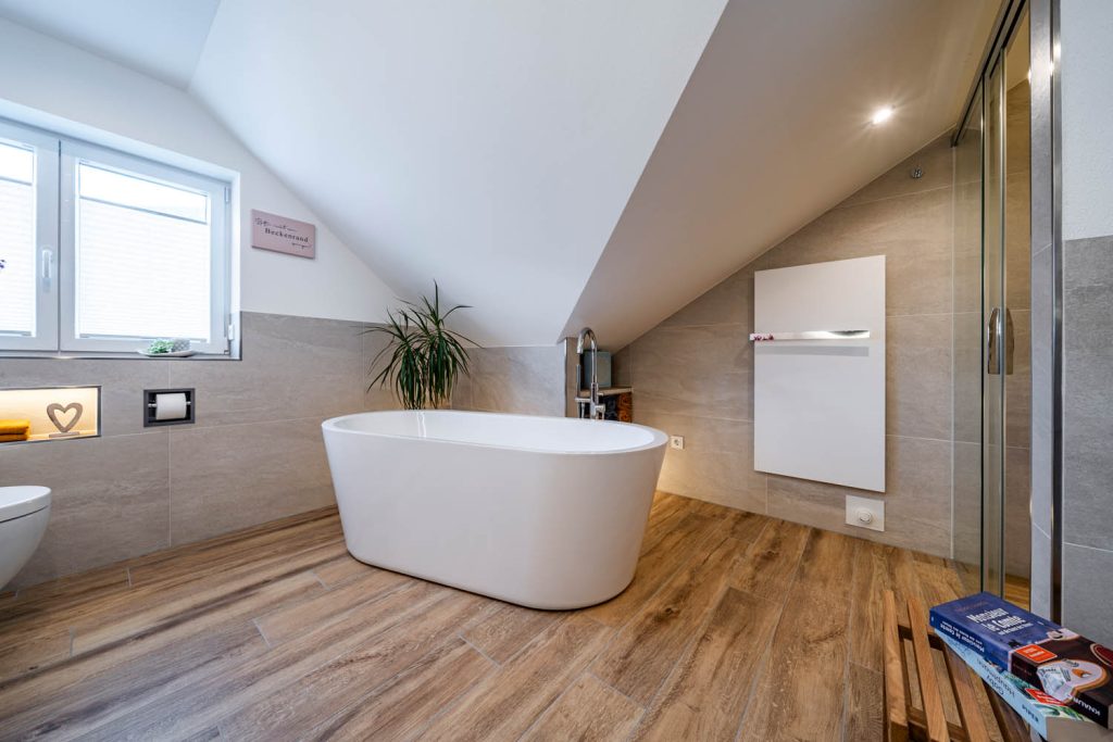 Freistehende Wanne unter der Dachschräge, rechts weißer Flächenheizkörper