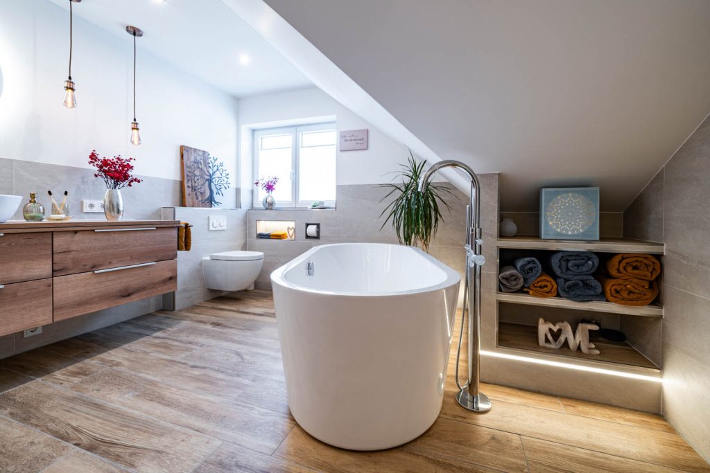 Badewanne mit Standarmatur, links Waschtisch, hinten Regal unter der Schräge