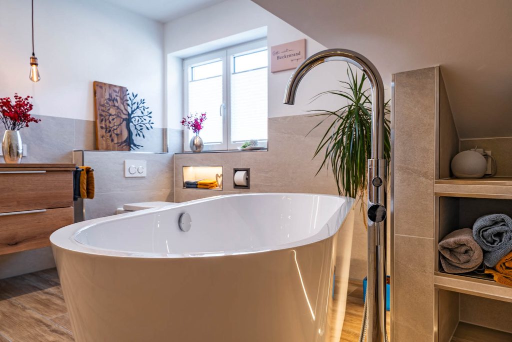 Freistehende Wanne mit Standarmatur, rechts Regal mit Handtüchern