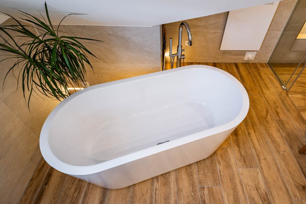 Ovale Badewanne von oben auf Boden in Holzoptik