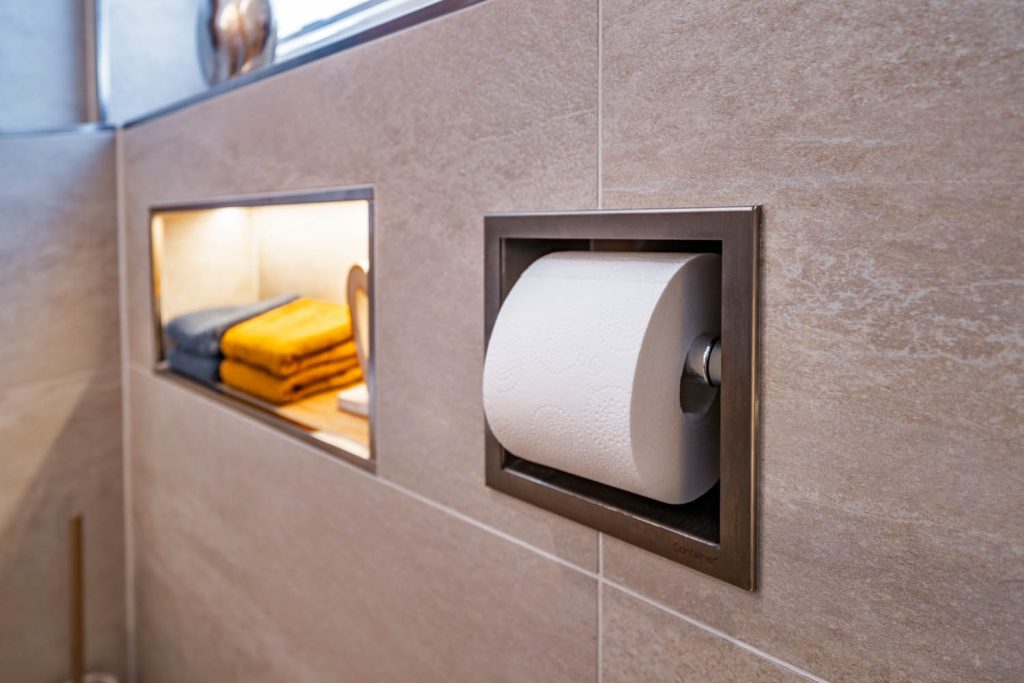 Eingelassener Papierhalter neben beleuchteter Handtuchnische