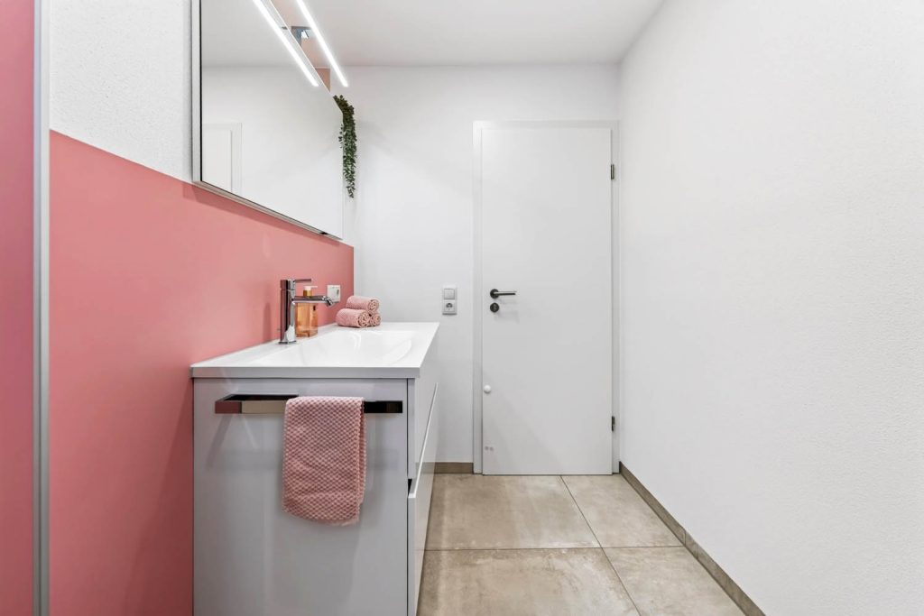 Seitlicher Blick auf den Waschtisch mit Spiegelschrank, im Hintergrund die weiße Badtür