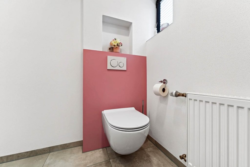 Wand-WC vor rosé Vorwand, rechts Papierhalter und Heizkörper