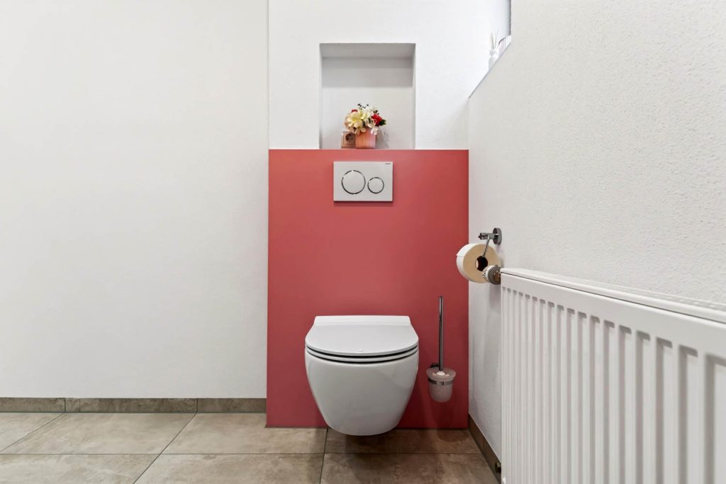 Frontalansicht des Wand-WCs mit rosé Vorwand, Wandnische und Heizkörper