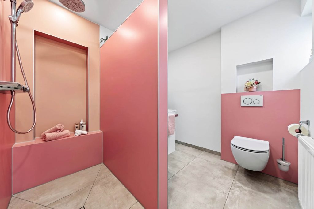 Dusche mit gemauerter Sitzbank in Rosé, rechts der Blick auf das Wand-WC