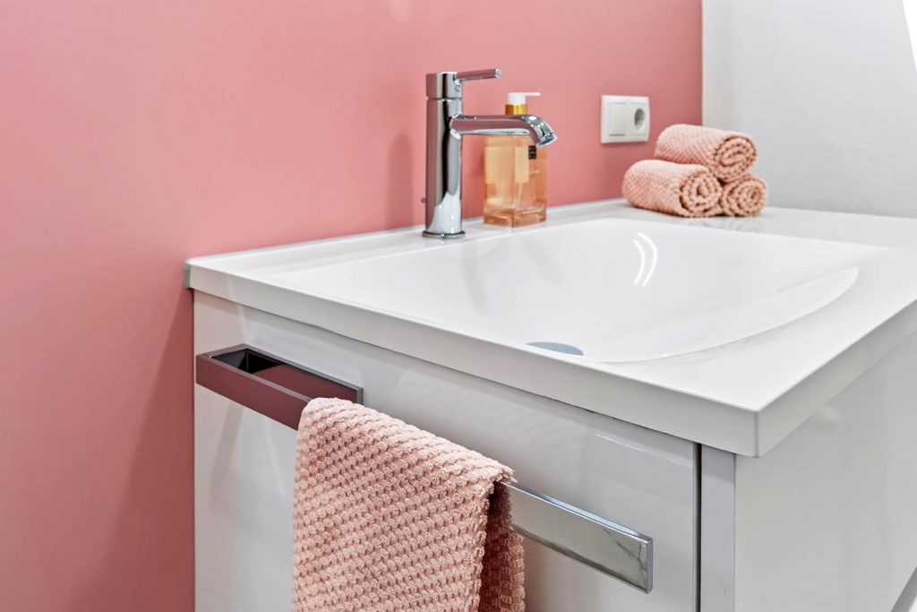 Waschtisch mit Handtuchhalter am Unterschrank und rosa Handtuch