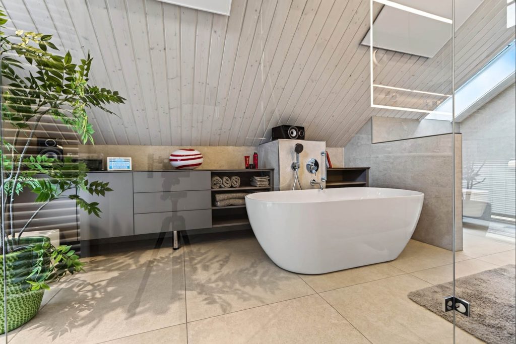 Weiter Blick über die freistehende Wanne auf die Regal- und Schrankfront unter der Dachschräge