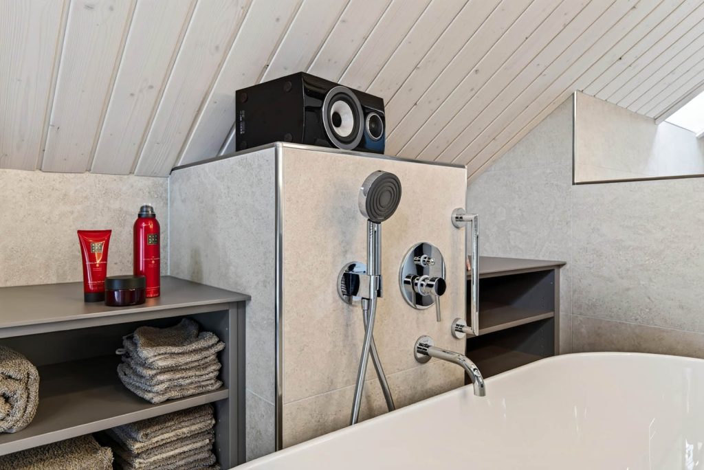 Detail der Vorwand mit Wannenarmatur, Haltegriff und Handbrause über dem Wannenrand
