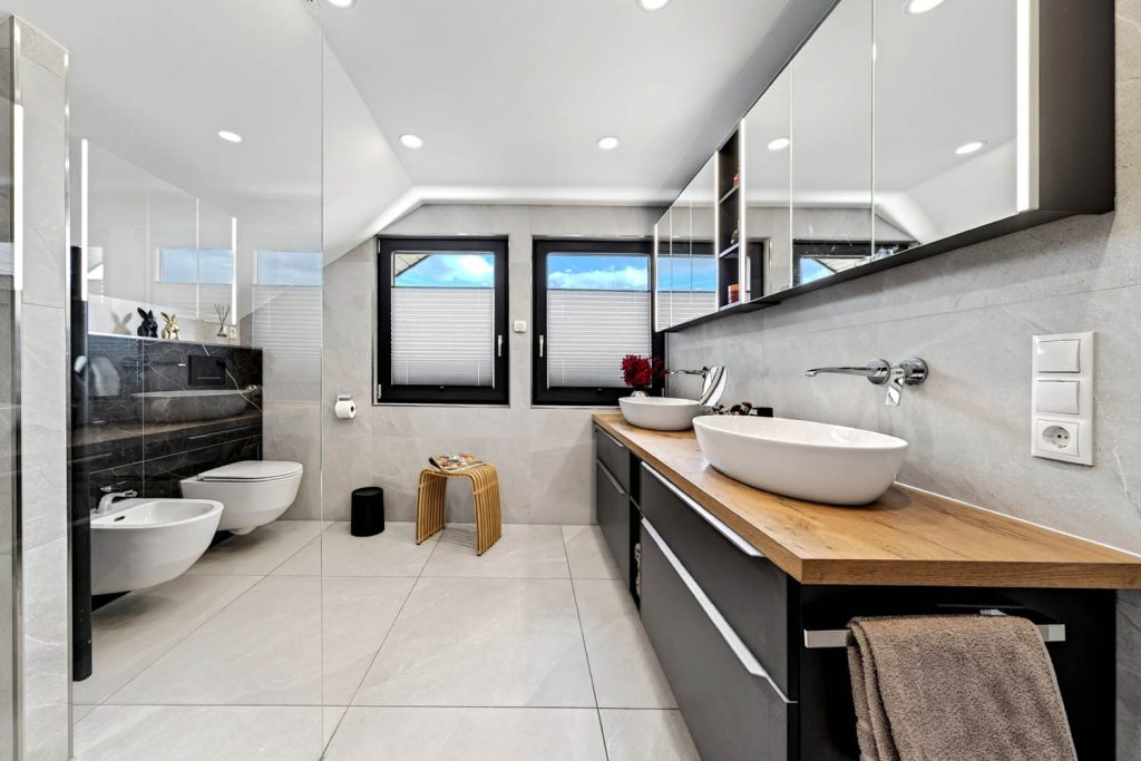 Langer Waschtisch mit Holzplatte und schwarzem Unterschrank, hinten Bidet, WC und Fenster