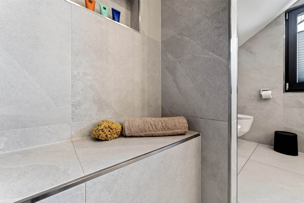 Geflieste Sitzbank in der Dusche mit Handtuch und Schwamm