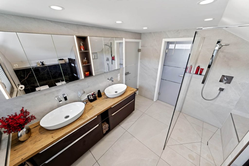 Waschtisch mit zwei Becken, rechts die Dusche mit Glaswand und Badtür