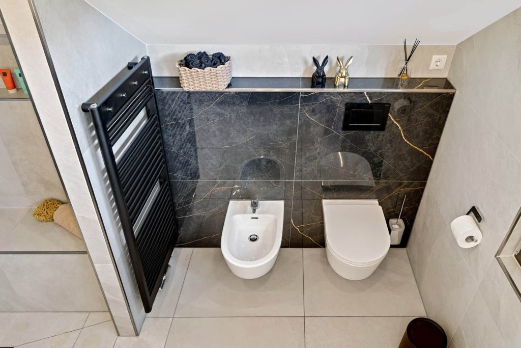 WC-Bereich von oben mit Bidet, WC, Ablage und schwarzem Handtuchheizkörper