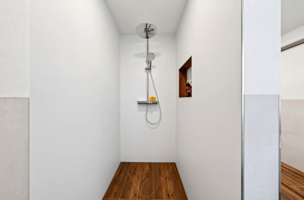 Bodengleiche Dusche mit Holzoptik-Boden, Brausestange und beleuchteter Wandnische