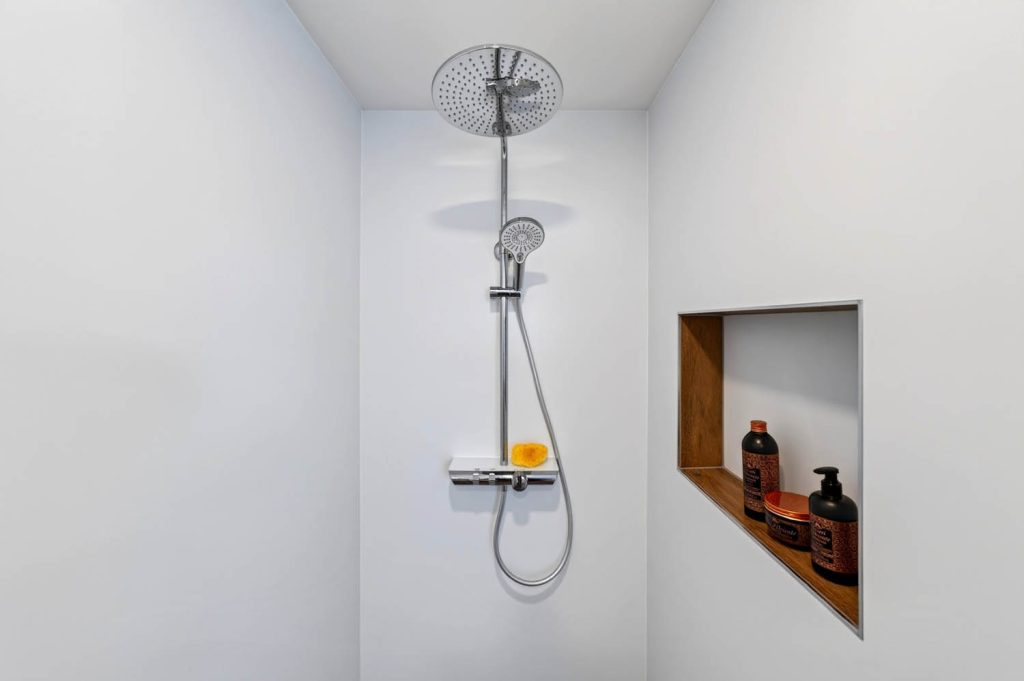 Duschsystem mit Kopfbrause, rechts eine Wandnische mit Holzrahmen
