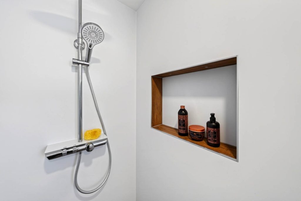 Brausestange mit Thermostat-Ablage, daneben Nische mit Holzeinfassung