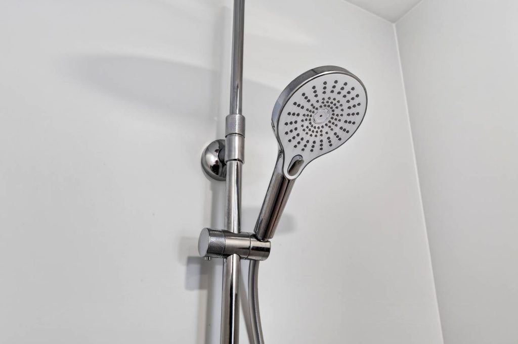 Handbrause an der Brausestange vor weißer Wand