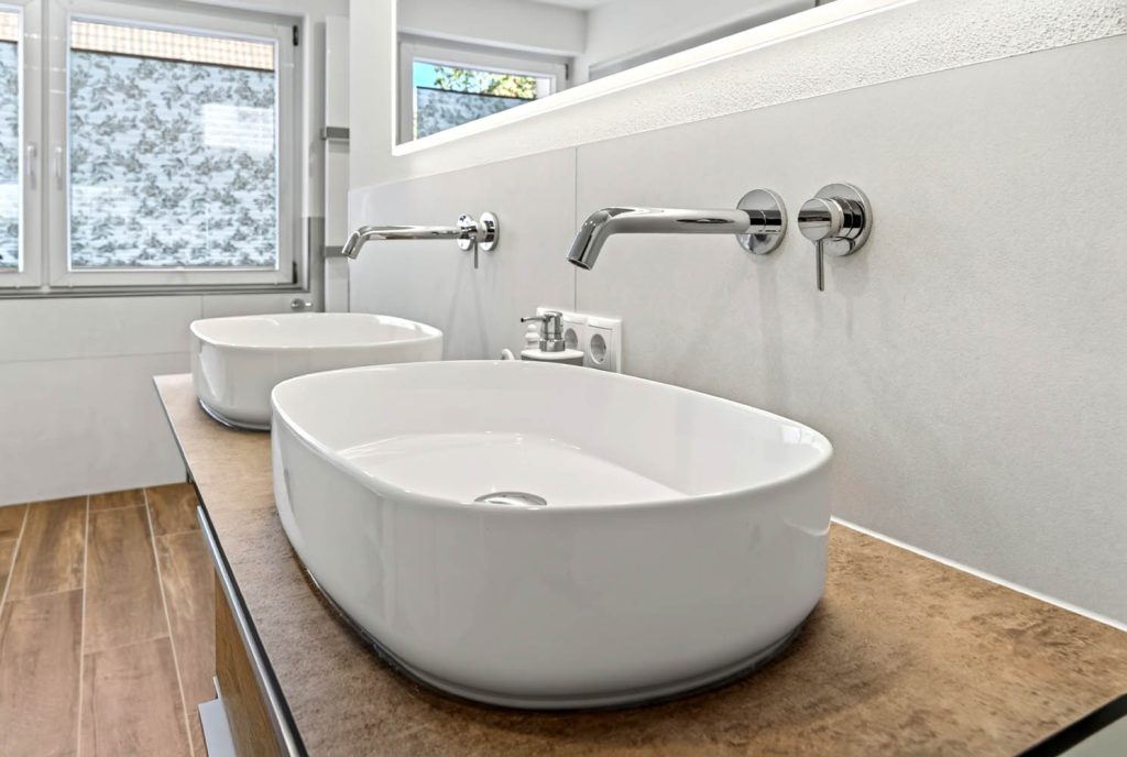 Ovale Aufsatzbecken mit Wandarmaturen auf der Waschtischplatte