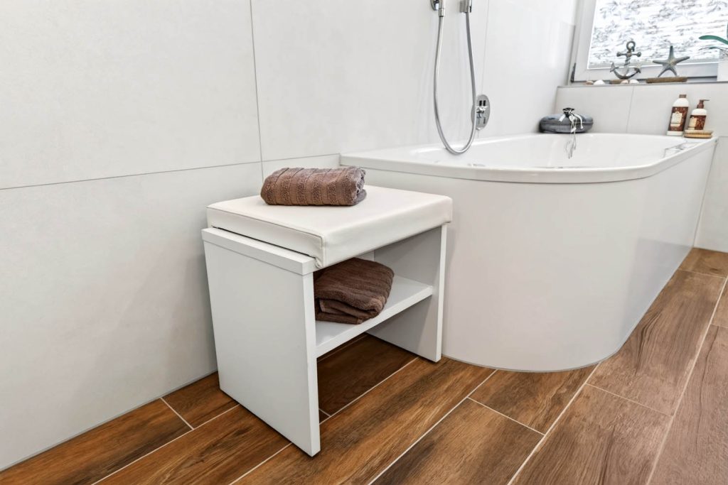 Badewanne mit gepolsterter Sitzbank, dahinter Fenster mit Dekoration