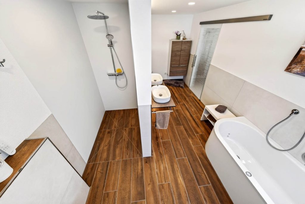 Blick in die Dusche neben der Vorwand, rechts die Badewanne