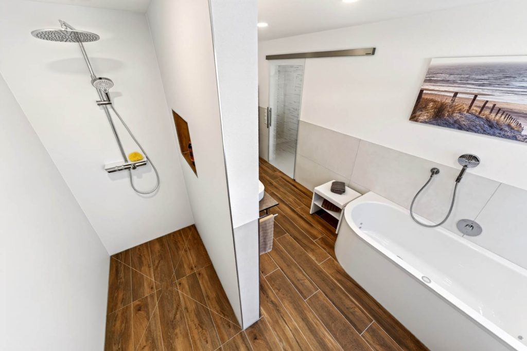 Dusche hinter der Vorwand mit Brausestange, rechts Badewanne unter dem Wandbild