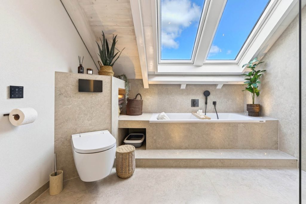 Wand-WC und Badewanne mit Podest unter der Dachschräge, rechts Glaswand der Dusche